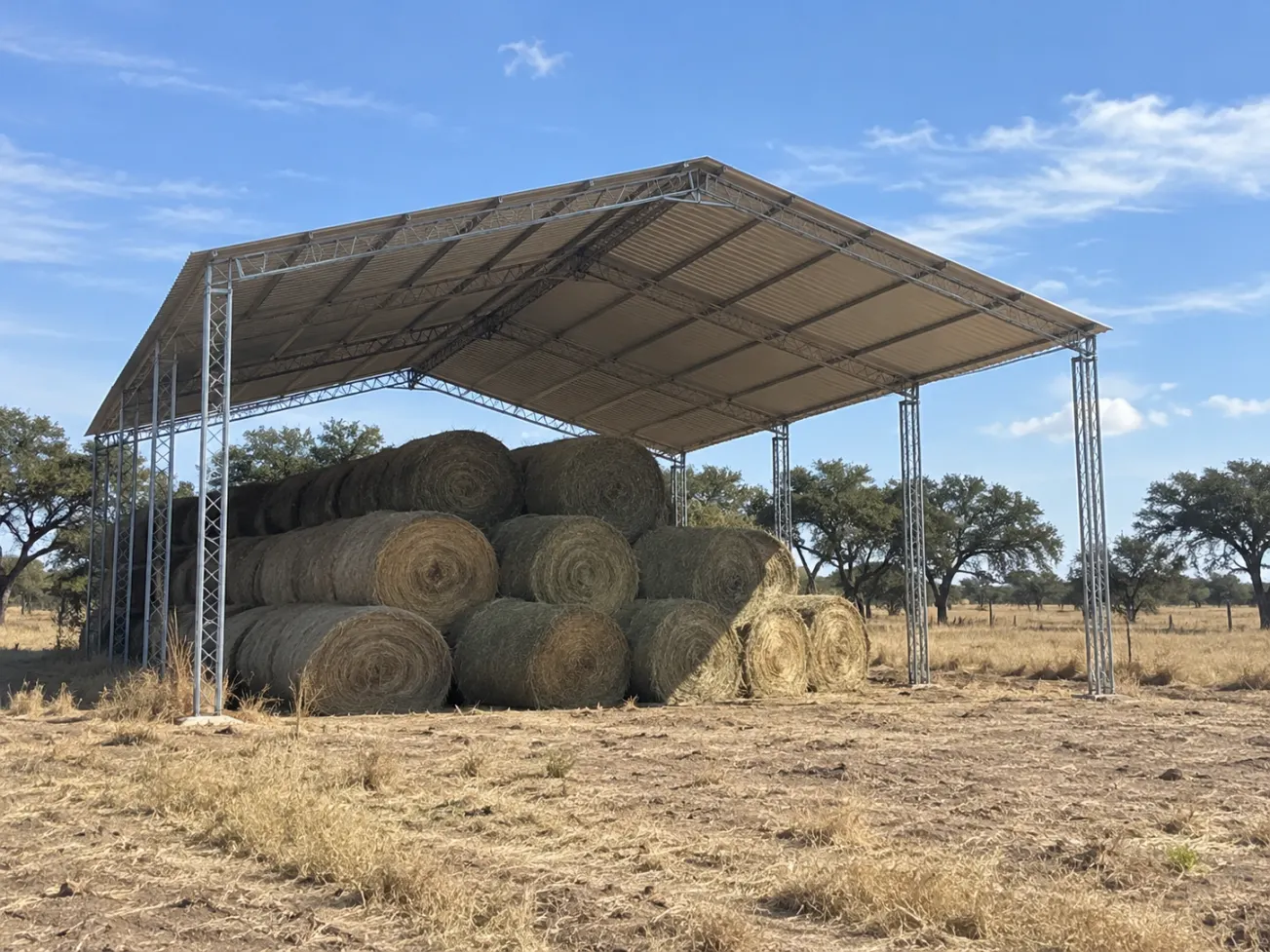 Tinglado de chapa con rollos de pasto en un campo de La Pampa